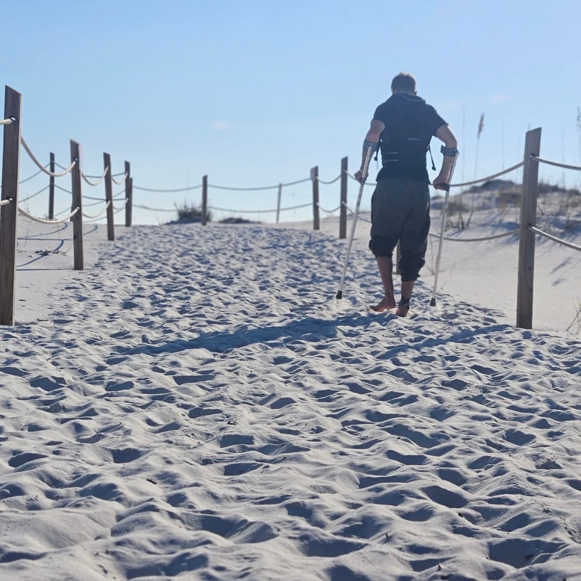 Michael Cavett walking on the beach with crutches