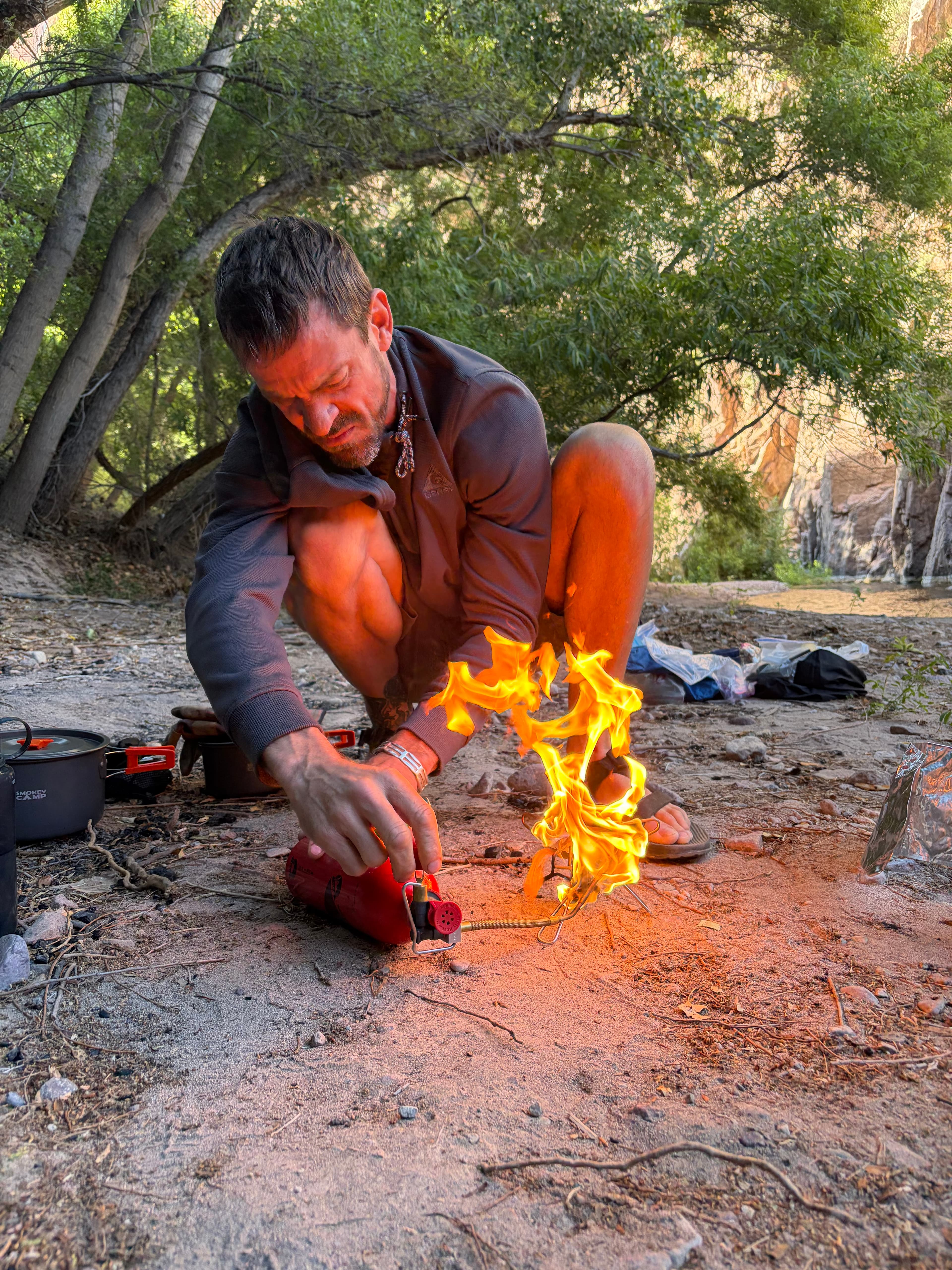 Michael Cavett lighting a campfire at a creekside camp